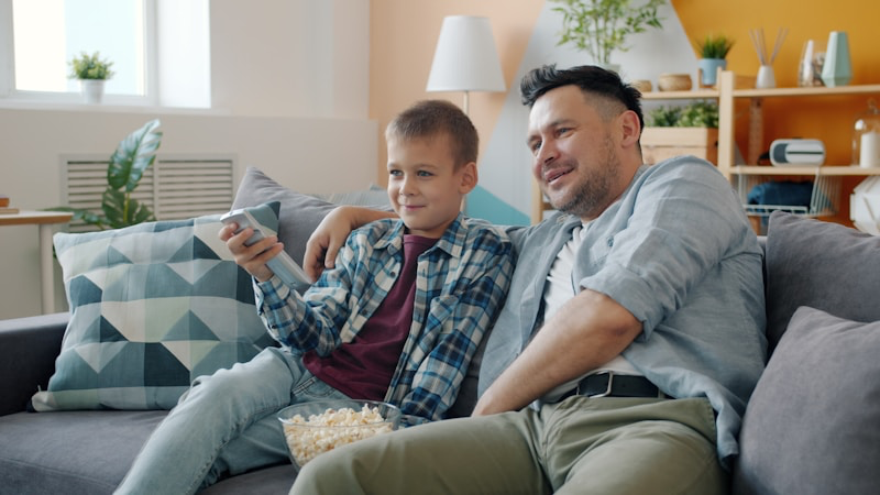 Padre e hijo viendo fútbol en casa - Plan IPTV Élite 3 dispositivos premium